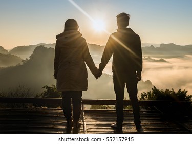silhouette teenager lovers couple over natural background at the mountain and holding hands looking in the Sun rise :black shadow loving people hug and kiss:love and valentines concept.