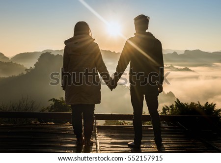 silhouette teenager lovers couple over natural background at the mountain and holding hands looking in the Sun rise :black shadow loving people hug and kiss:love and valentines concept.