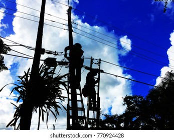 Silhouette of telecommunication workers on ladders pulling wires for new high speed fiber optics service in a residential neighborhood. 