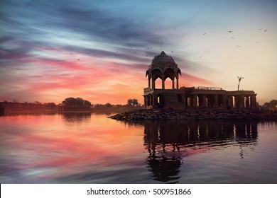 Silhouette Of Temple On The Gadi Sagar Lake At Pink Vibrant Sunset Sky In Jaisalmer, Rajasthan, India