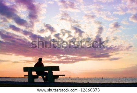 silhouette of thinking man on bench by sunset