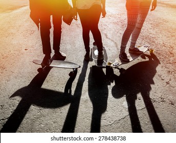 Silhouette Three Friends Skateboarders In The Skatepark. Lower Part Of The Body Two Young Girls And One Guy On Longboard And Skateboard