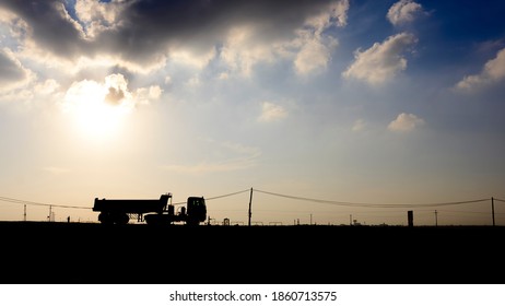 Silhouette of tipper dump truck in the oilfield at sunset 