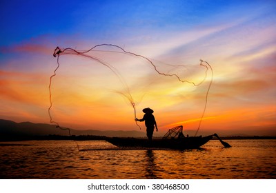 Silhouette of traditional fishermen throwing net fishing lake at sunrise time.(The casting people living along the River)