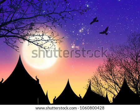 Silhouette of the traditional Thai house style and leafless trees with blurred full moon and night sky background on Thai architecture design concept 