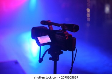 Silhouette of a TV camera, live concert, the shining stage blue light on the theatrical smoke background