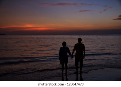 Silhouette of two adults at the coast