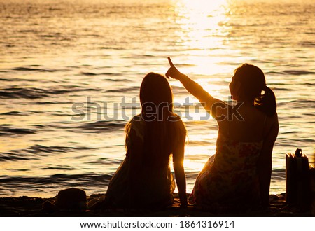 Silhouette two Asian young woman talking on sunset beach