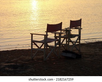 Silhouette Of Two Chairs By The Beach At Sunset