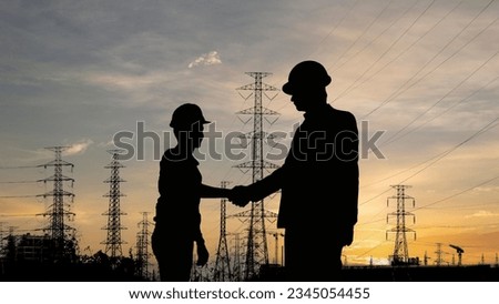 Silhouette of Two electrical engineers stand shake handsat a power station ,ฺ Business cooperation Partner concept