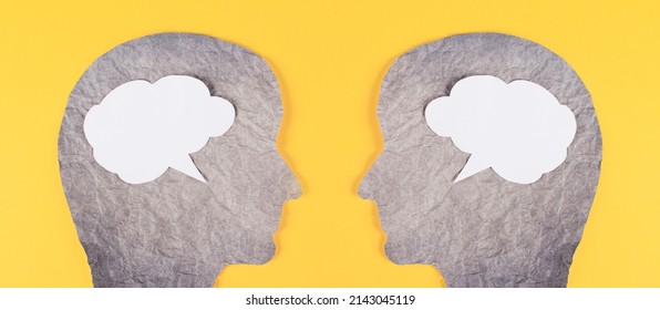 Silhouette of two faces, speech bubble in white color, copy space for text, communication, having an opinion and discussion, free speech, people talking, yellow background - Shutterstock ID 2143045119
