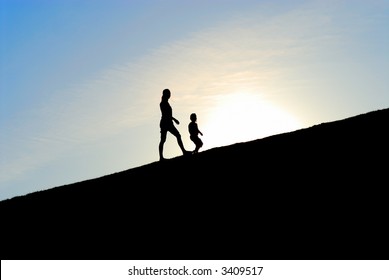 Silhouette of two girls walking together up the hill against the sunset
