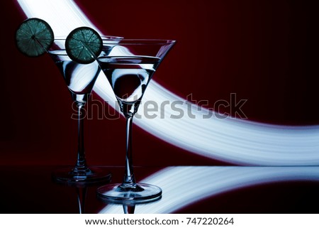 silhouette of two glasses with a cocktail and lemon in a nightclub