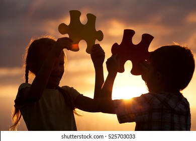 Silhouette of two happy children which playing on the field at the sunset time. They having fun on the nature. Concept of the kids are ready to go to school.