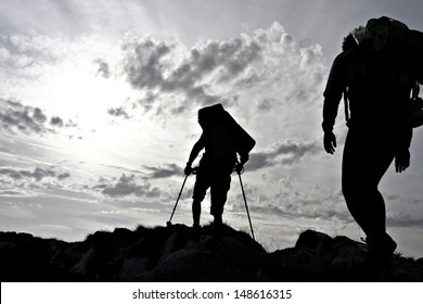 Silhouette Of Two Hikers On A Mountain Ridge