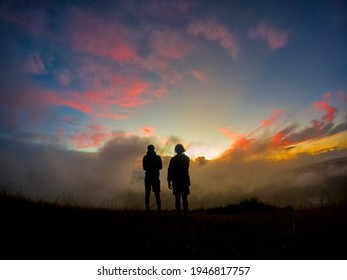 Silhouette Of Two Hikers Watching The Sun Rise In The Mist At 'Le Pouce' Mountain