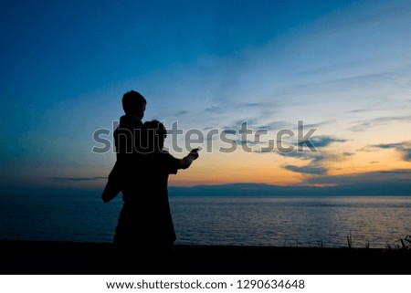 Silhouette of two kids on the background of a beautiful summer sunset over the sea. The Island Of Ischia, Italy
