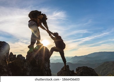 Silhouette Two Male hikers climbing up mountain cliff and one of them giving helping hand. People helping and, team work concept. - Shutterstock ID 1866436603