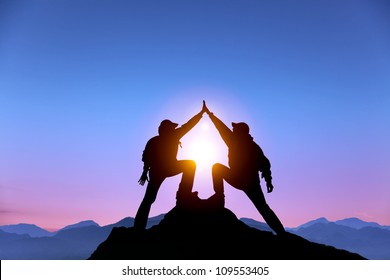 The Silhouette of two man with success gesture standing on the top of mountain