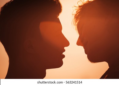 Silhouette of two men about to kiss