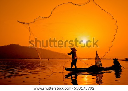 Silhouette two men fishing on a fishing boat in the Mekong River at sun rise