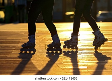 Silhouette Of Two Pairs Of Legs On Roller Skates