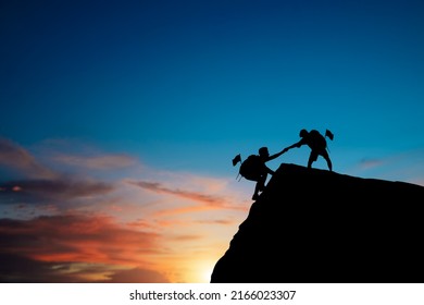 Silhouette Of Two People Helping Each Other Hike Up On A Mountain At Sunrise. Giving A Helping Hand, And Active Fit Lifestyle Concept. Couple Hiking Help Each Other. Together They Will Succeed.