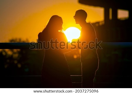 Silhouette of two people in love against the backdrop of the setting sun. Romance in relationships and nature