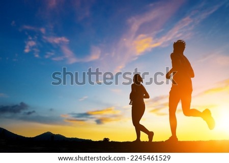 Silhouette of two person running on road go to dream. Fitness runner outdoor with sunset background.