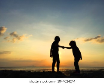 Silhouette of two sibling playing together at the beach on sunset - Shutterstock ID 1044024244