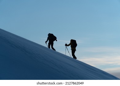 Silhouette Of Two Skiers At Sunrise