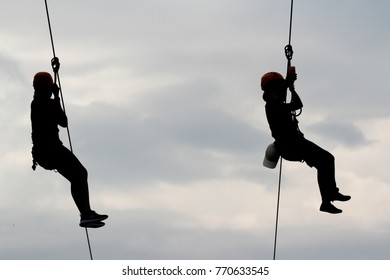 Silhouette Of Two Tourists Wearing Casual Clothing Are Playing Zip Line And Selfie