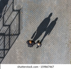 Silhouette Of A Two Womans Casting A Long Shadow On A Cobble Stone Road