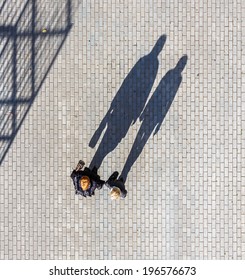 Silhouette Of A Two Womans Casting A Long Shadow On A Cobble Stone Road