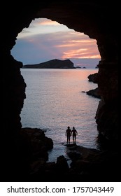 Silhouette of two women in a cove in Ibiza with the sunset in the background. Friendship and human relations