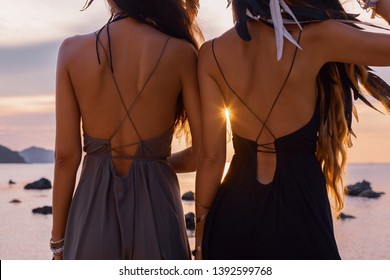 silhouette of two young beautiful girls having fun on the beach at sunset 