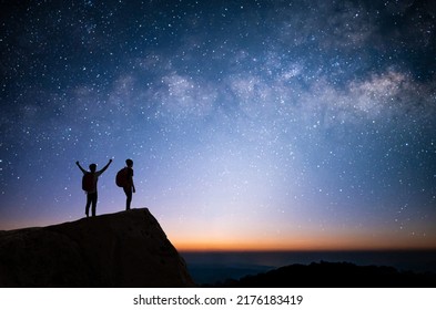 Silhouette of two young man standing, open arms and watched the star, milky way and night sky on top of the mountain. They enjoyed traveling and was successful when he reached the summit. - Shutterstock ID 2176183419