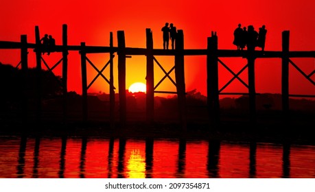 A silhouette of the U Bein bridge over the Taungthaman Lake at sunset in Myanmar - Shutterstock ID 2097354871