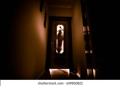 Silhouette Of An Unknown Shadow Figure With Hands On A Door Through A Closed Glass Door. Horror Concept