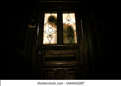 Silhouette of an unknown shadow figure on a old wooden door through a closed glass door. The silhouette of a human in front of a window at night. Scary scene halloween concept