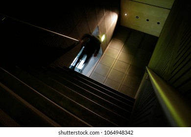 Silhouette of unrecognizable man going upstairs from underground. Abstract tilt photo on the subject of urban architecture and lifestyle. - Shutterstock ID 1064948342