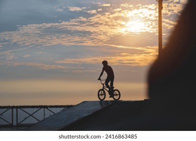 Silhouette unrecognizable Young man doing ramp jump stunt on bmx bicycle on sunset. - Powered by Shutterstock