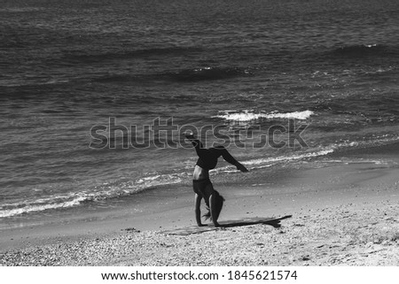 Silhouette of unrecognizable young woman practicing handstand at sea beach. Tel-Aviv, Israel. Black white photo. Fitness in nature background. Healthy lifestyle concept. Waves metaphor.