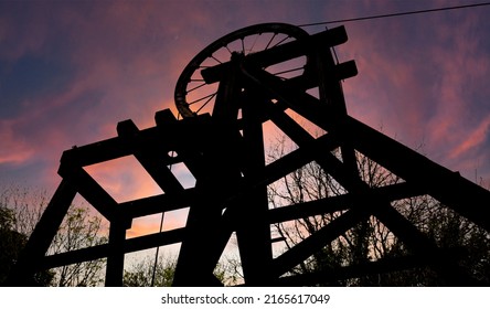 silhouette of a vintage mining wheel during a impressive sunset