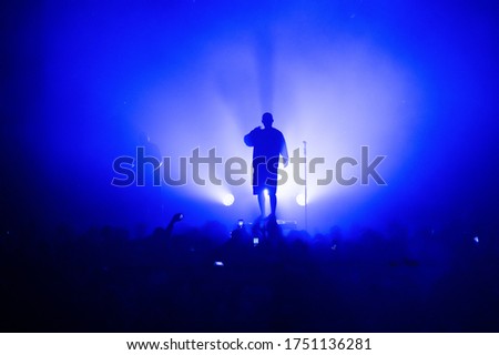 silhouette of a vocalist and microphone stand on stage in a blue haze