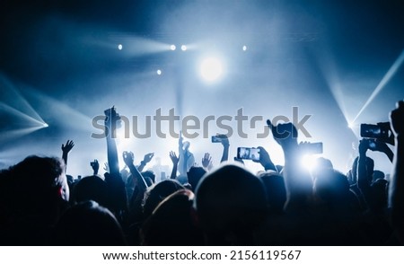 silhouette of the vocalist stands in a fog in the rays of light. concert crowd in front of bright stage lights. Dark background, smoke, concert  spotlights