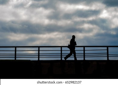 Silhouette of a walking man against a background against a cloudy sky. Rush concept