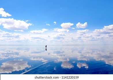 Silhouette walking on the calm water of the lake Elton, the biggest salt lake in Europe, with amazing mirror reflections of sky and clouds, Russia, Volgograd oblast - Powered by Shutterstock