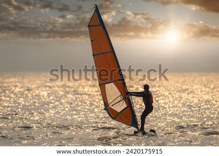 Silhouette water sportsman under play windsurfing is summer sport activity concept with sun sky background. 
