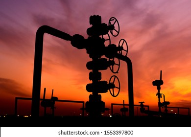 Silhouette of well head manifold in the oilfield at sunset